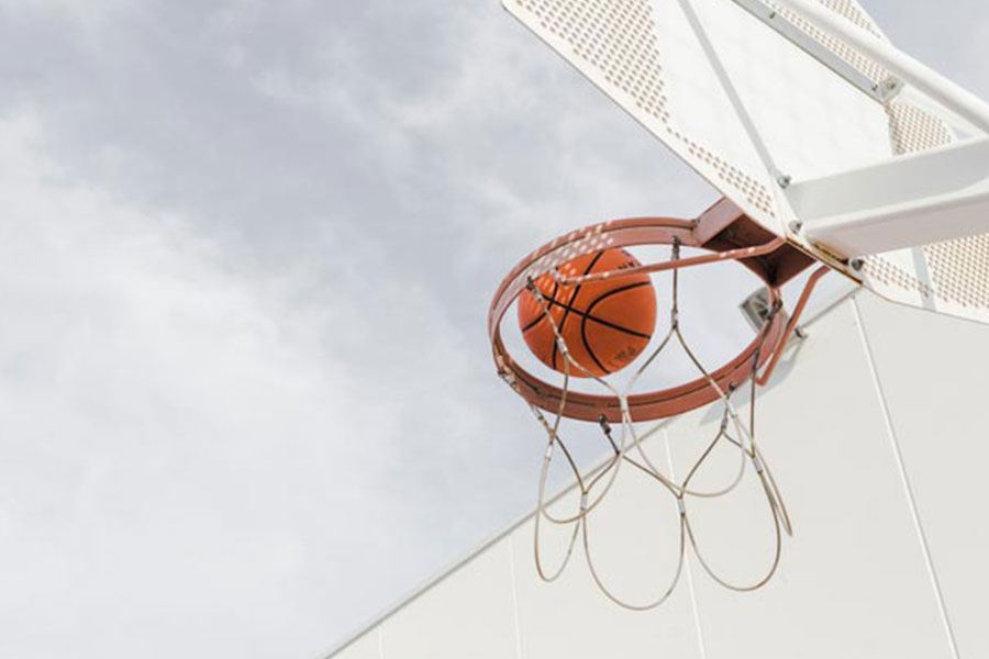 A basketball dropping through a hoop against the sky