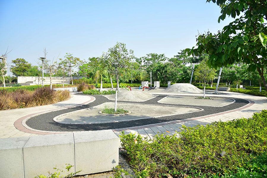 A children’s play area with a winding track set among lawns and young trees