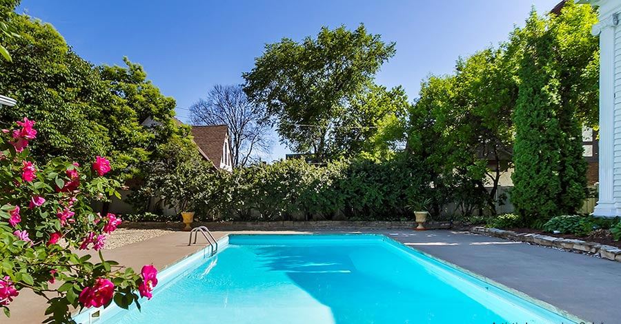 The swimming pool with clear blue water, surrounded by flowering plants and trees